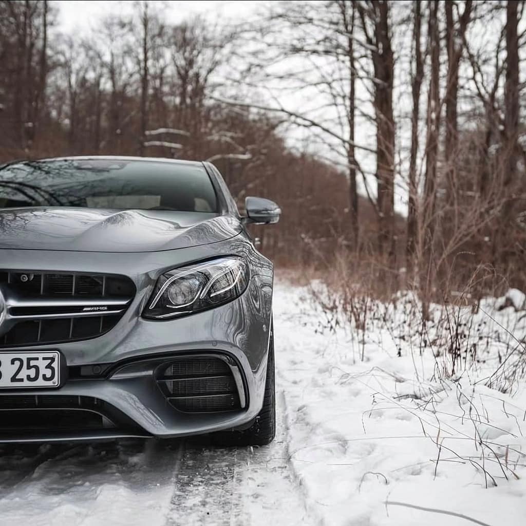 Mercedes-AMG E-Klasse W213 in Silber im verschneiten Wald mit sportlicher Frontansicht