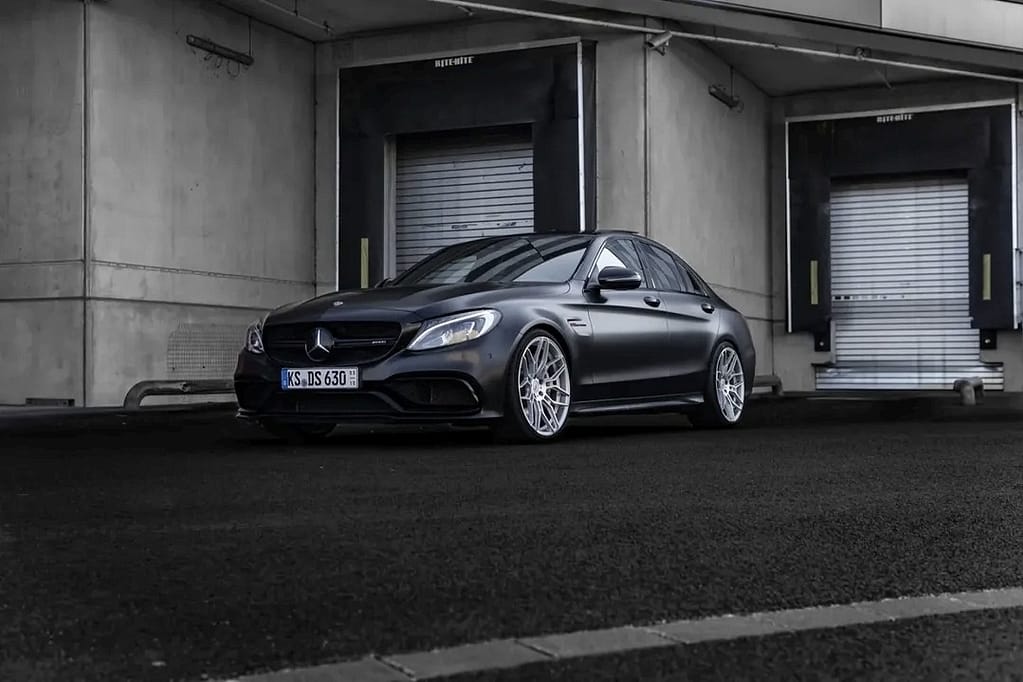 Mercedes-AMG C63 W205 in mattschwarz mit V8 Biturbo Motor in urbaner Industrieumgebung bei nasser Straße fotografiert