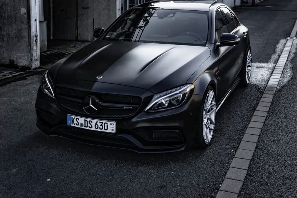 Mercedes-AMG C63 W205 in mattschwarz mit V8 Biturbo Motor in urbaner Industrieumgebung bei nasser Straße fotografiert