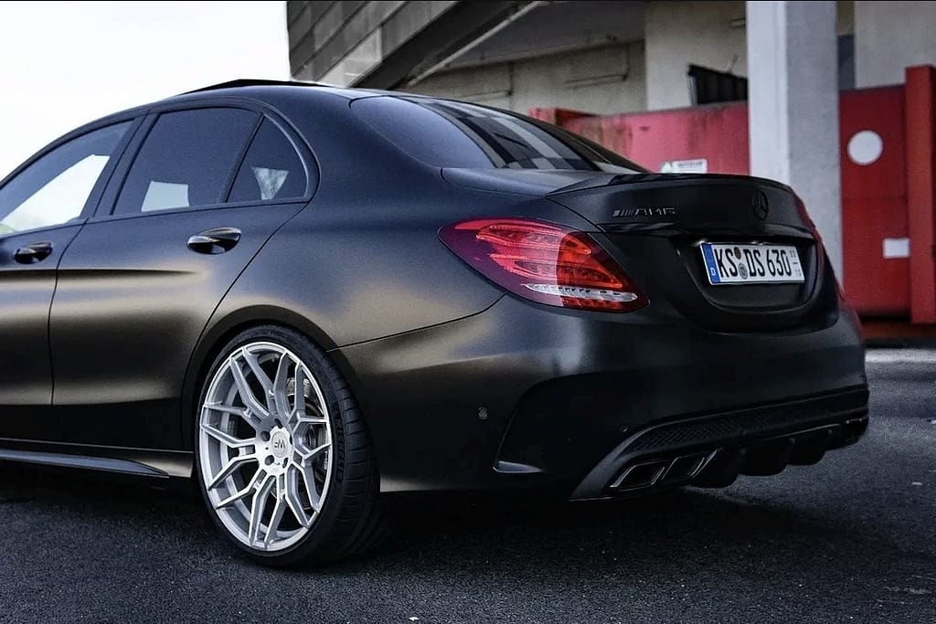 Mercedes-AMG C63 W205 in mattschwarz mit V8 Biturbo Motor in urbaner Industrieumgebung bei nasser Straße fotografiert