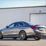 Mercedes-AMG E63 in Heck-Seitenansicht vor einer weißen Industriehalle mit Rolltor, sportliche AMG-Limousine mit markanter Heckpartie und vier Endrohren.