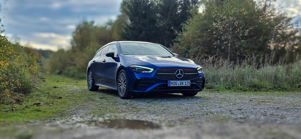 Mercedes-Benz CLA blau Front-Seitenansicht auf Waldweg in natürlicher Landschaft