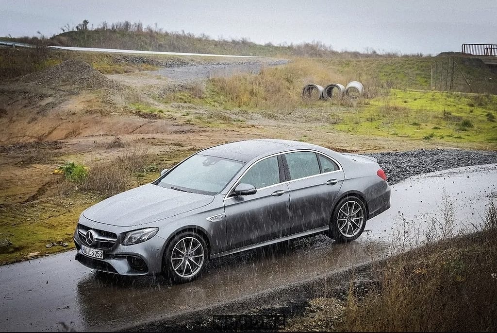 Mercedes-AMG E-Klasse W213 Limousine in silber bei Regen auf nasser Straße in dynamischer Fahraufnahme