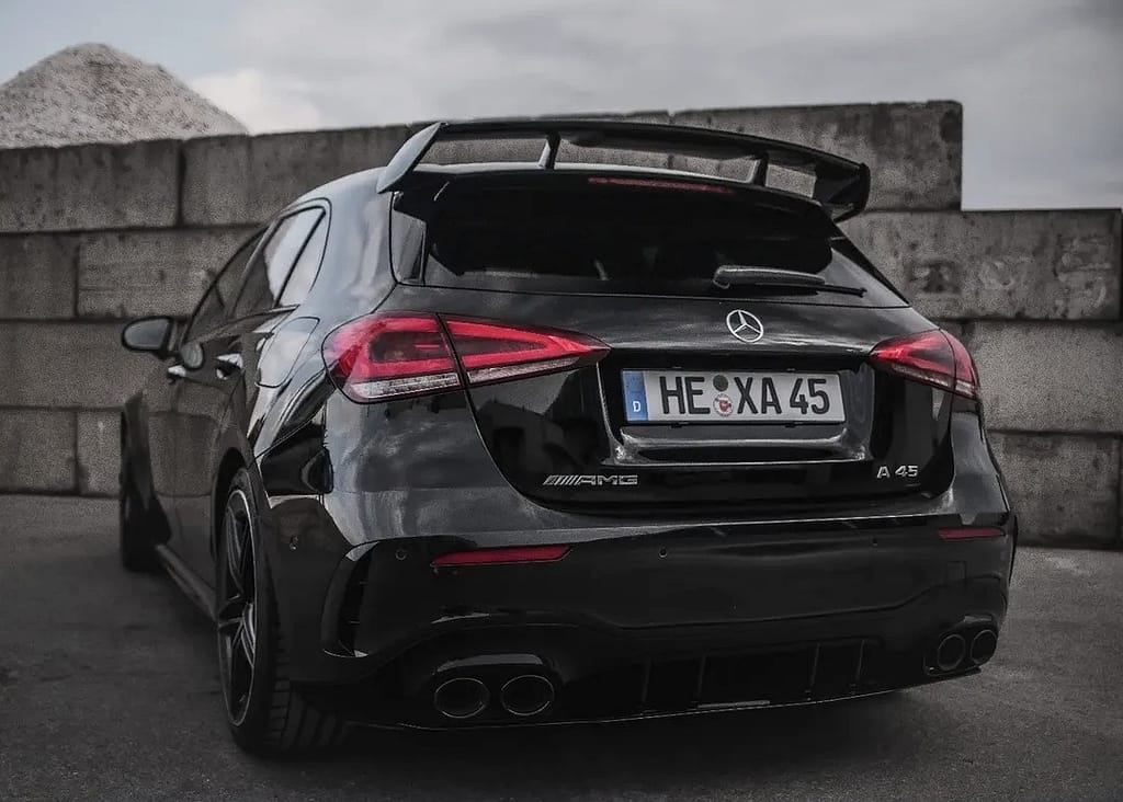 Schwarzer Mercedes-AMG A 45 S (W177) vor industrieller Hafenkulisse mit markantem Panamericana-Grill, roten Bremssätteln und sportlichem Aerodynamikpaket. Hochwertige Automotive Fotografie mit Fokus auf Performance und Design.
