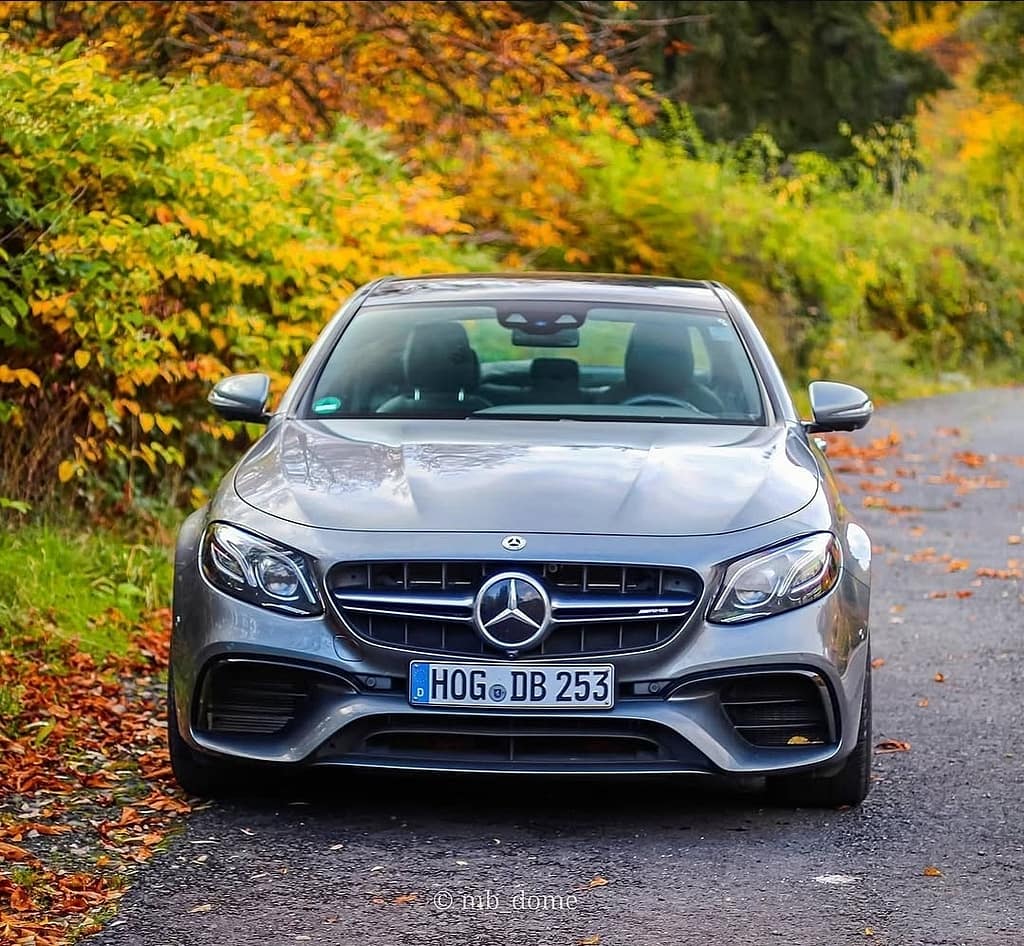 Mercedes-AMG E63 in Frontansicht auf einer Straße mit herbstlichen Bäumen und buntem Laub im Hintergrund fotografiert