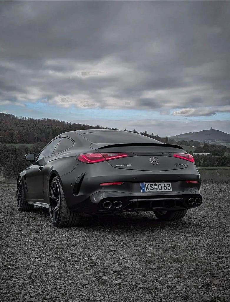 Mercedes-AMG CLE 53 Coupé C236 in mattem Graphitgrau auf Schotterfläche unter bewölktem Himmel mit AMG Panamericana-Grill, sportlichem Heckdesign und Performance-Optik fotografiert von MB-DOME Automotive Photography