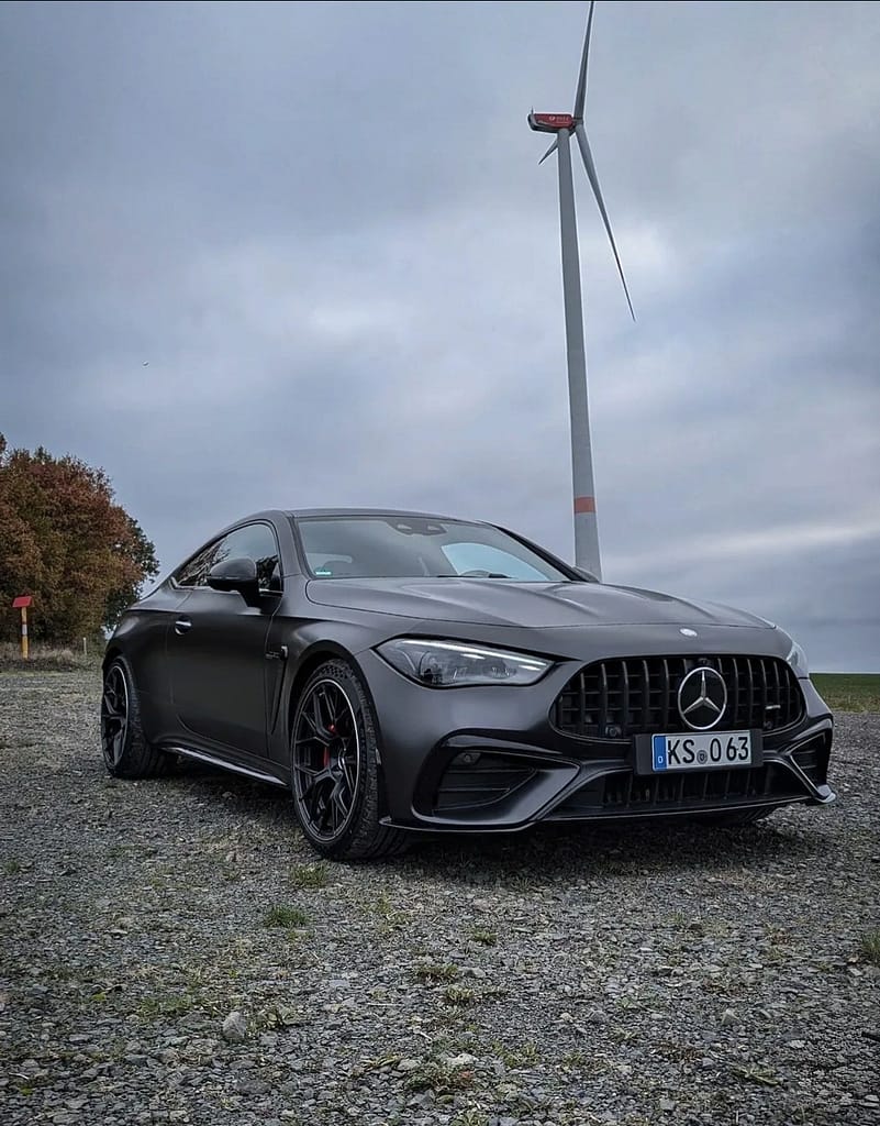 Mercedes-AMG CLE 53 Coupé C236 in mattem Graphitgrau auf Schotterfläche unter bewölktem Himmel mit AMG Panamericana-Grill, sportlichem Heckdesign und Performance-Optik fotografiert von MB-DOME Automotive Photography
