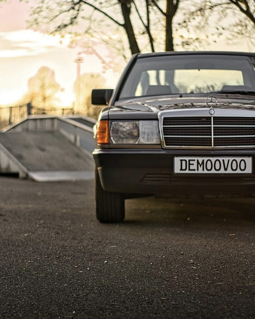 Klassischer Mercedes-Benz 190E W201 Frontansicht mit warmem Abendlicht und urbanem Hintergrund.