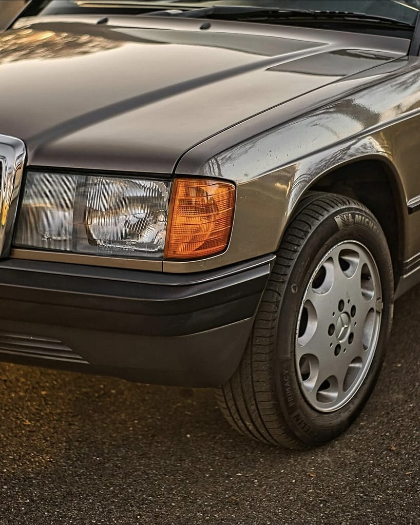 Detailaufnahme von Frontscheinwerfer und Felge eines Mercedes-Benz 190E W201