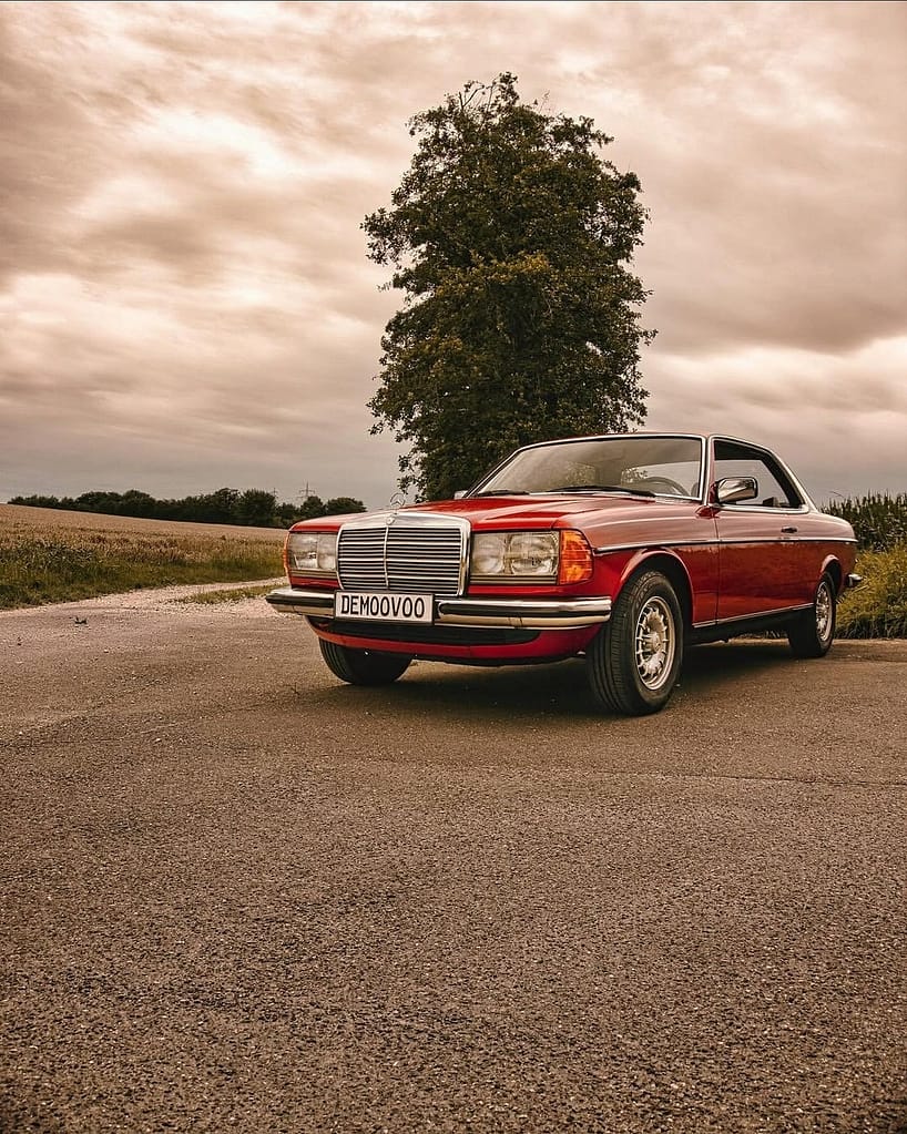 Mercedes-Benz C123 Coupé in klassischem Rot auf einer Landstraße mit Chromgrill und zeitlosem Design – hochwertige Automotive Photography von MB-DOME.
