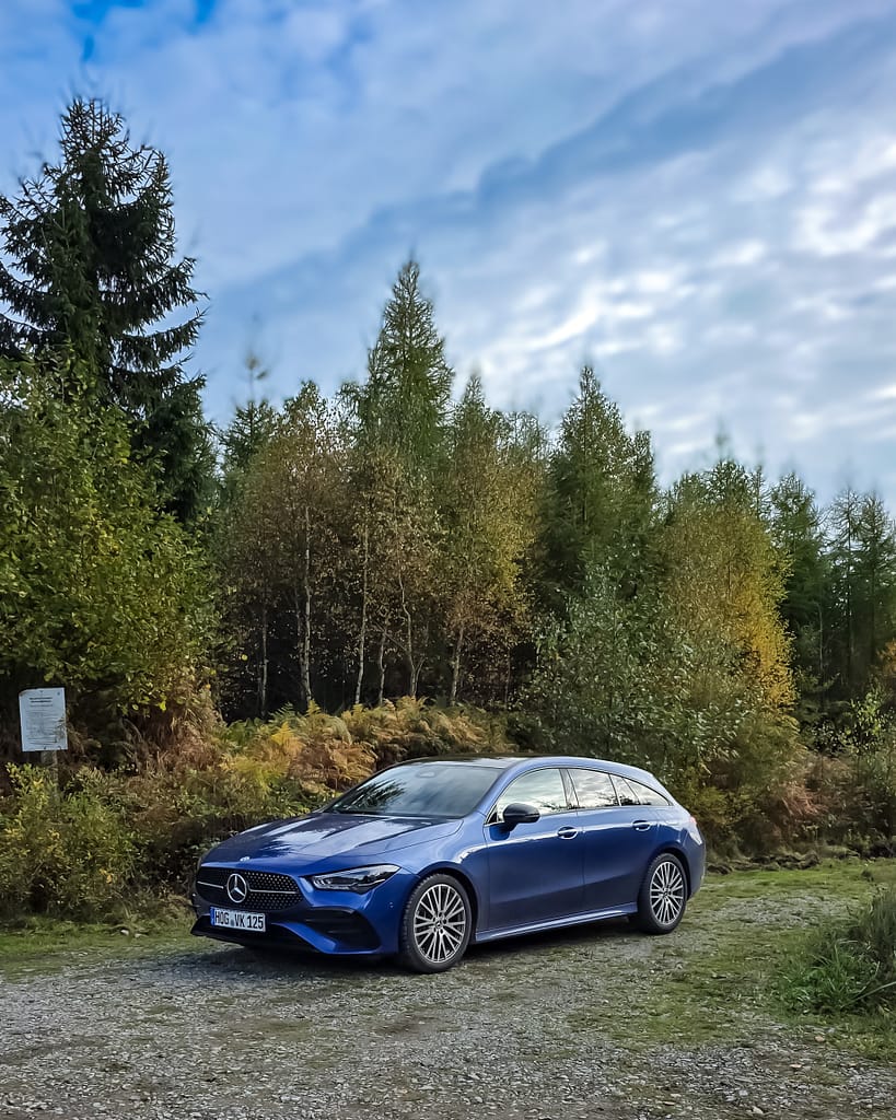 Mercedes-Benz CLA Shooting Brake blau Front-Seitenansicht auf Waldweg mit herbstlichen Bäumen