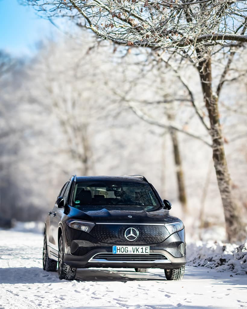 Mercedes-Benz EQB Front-Seitenansicht auf verschneiter Waldstraße im Winter