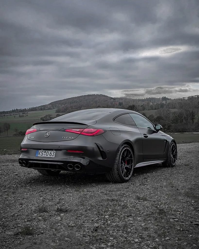 Mercedes-AMG CLE 53 Coupé C236 in mattem Graphitgrau auf Schotterfläche unter bewölktem Himmel mit AMG Panamericana-Grill, sportlichem Heckdesign und Performance-Optik fotografiert von MB-DOME Automotive Photography