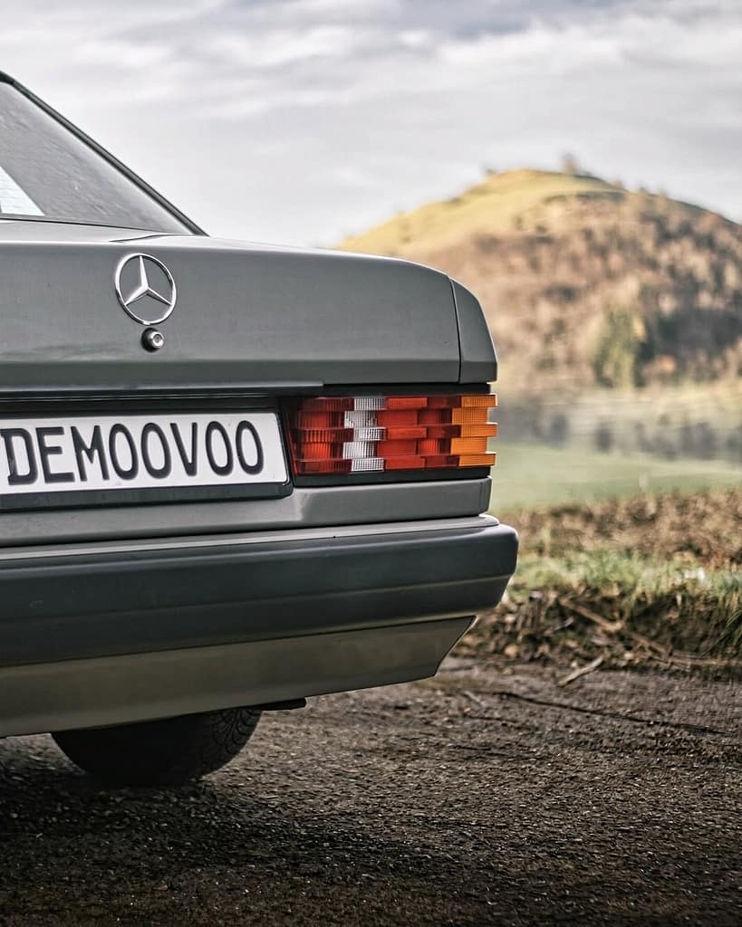Mercedes-Benz 190 E (W201) in grauer Lackierung vor einer malerischen Hügellandschaft – klassischer Mercedes-Youngtimer mit zeitlosem Design und eleganter Linienführung.