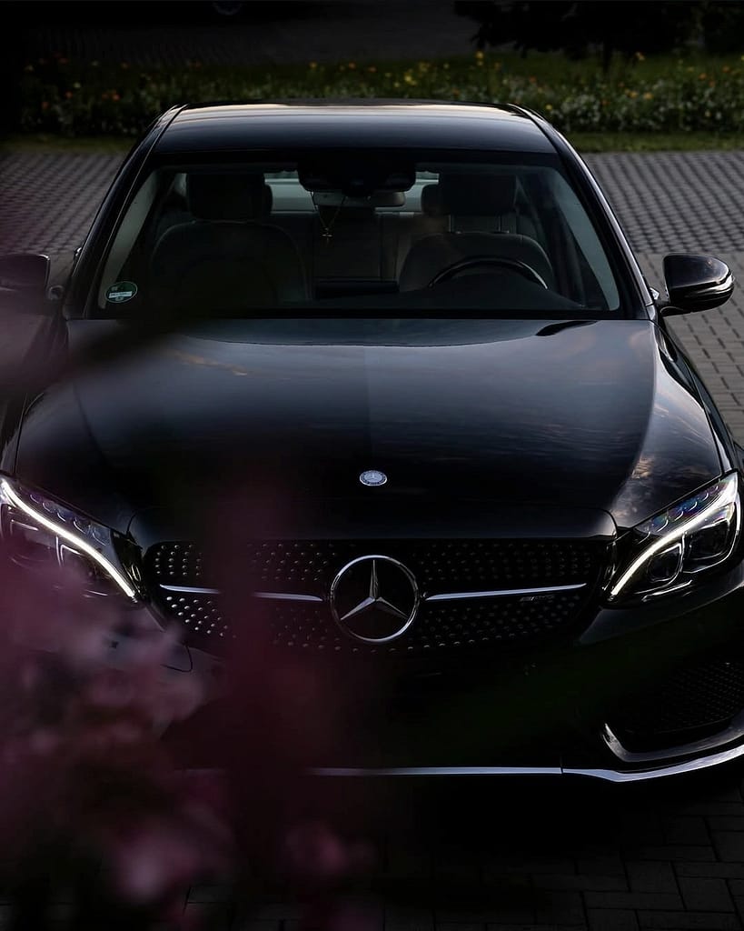 Mercedes-Benz C-Klasse Limousine (W205) in Schwarz während eines Fotoshootings bei Abenddämmerung mit Front-, Heck- und Detailaufnahmen vor moderner Architektur.
