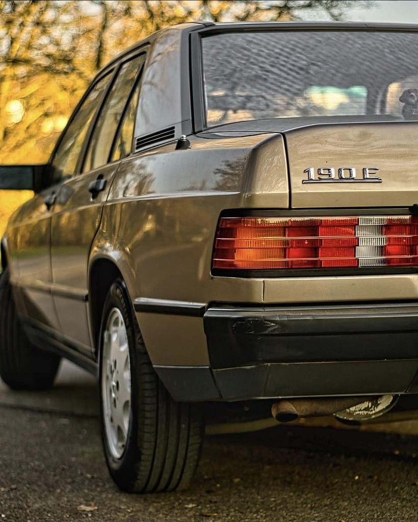 Heckansicht eines Mercedes-Benz 190E W201 in goldener Abendsonne mit klassischem Mercedes-Design