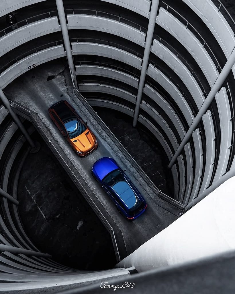 Mercedes-AMG C43 S205 in Orange und blaues Fahrzeug auf spiralförmiger Parkhausrampe aus der Vogelperspektive