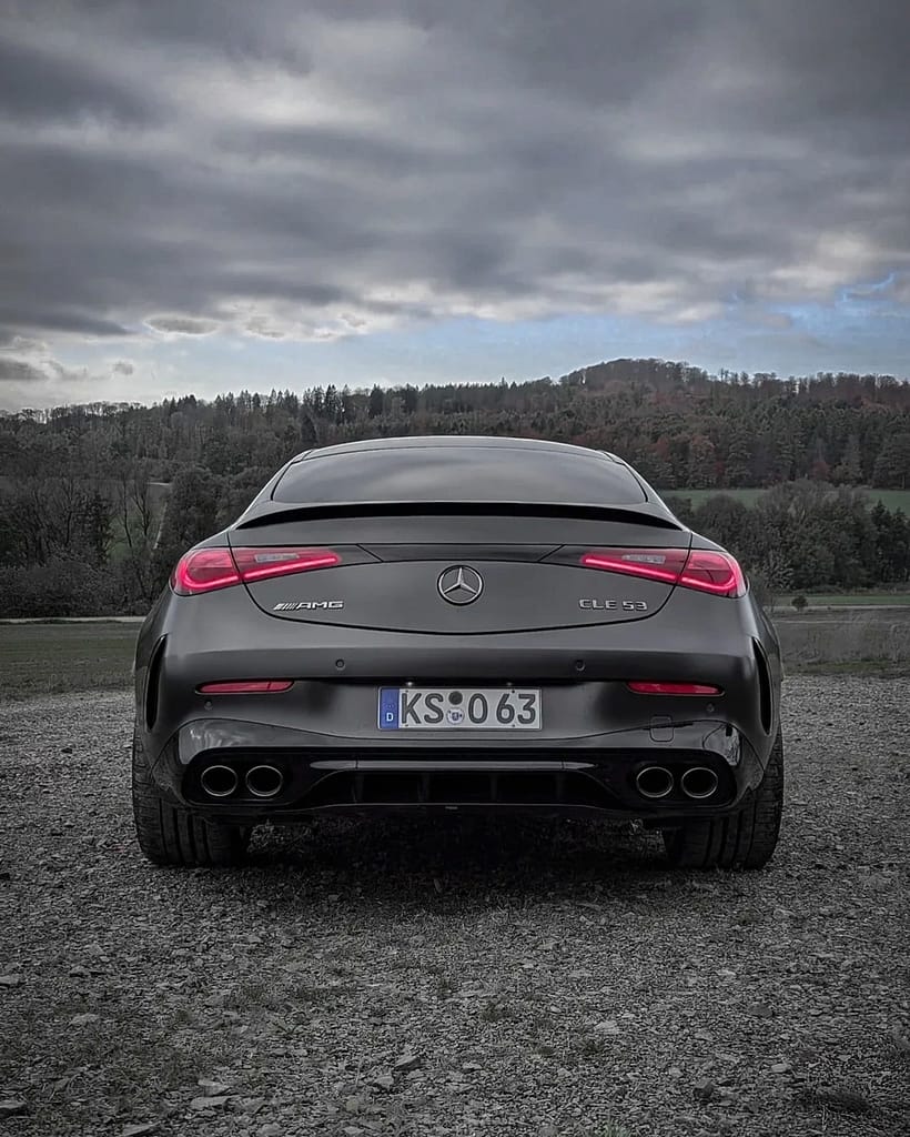 Mercedes-AMG CLE 53 Coupé C236 in mattem Graphitgrau auf Schotterfläche unter bewölktem Himmel mit AMG Panamericana-Grill, sportlichem Heckdesign und Performance-Optik fotografiert von MB-DOME Automotive Photography