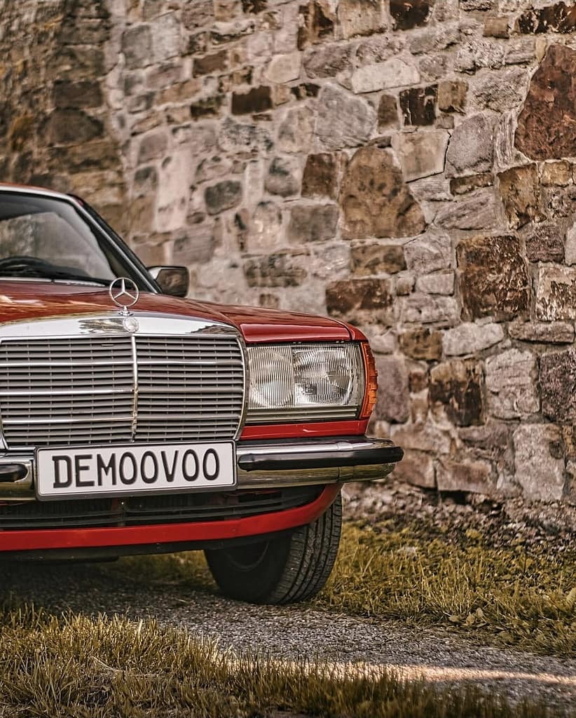Frontansicht eines roten Mercedes-Benz C123 Coupé mit klassischem Chromgrill und Mercedes-Stern.