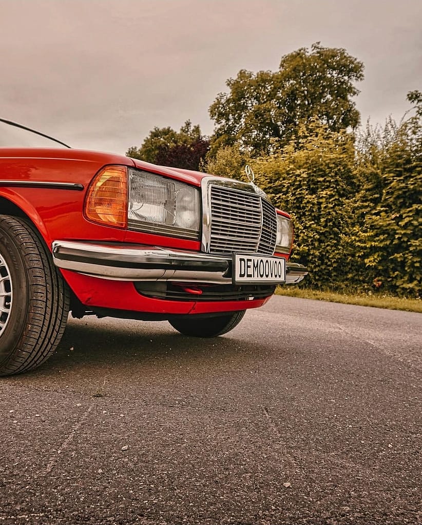 Mercedes-Benz C123 Coupé in klassischem Rot auf einer Landstraße mit Chromgrill und zeitlosem Design – hochwertige Automotive Photography von MB-DOME.