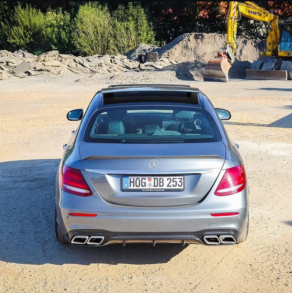 Mercedes-AMG E63 in Silber in symmetrischer Heckansicht auf einem Industriegelände mit Bagger im Hintergrund fotografiert