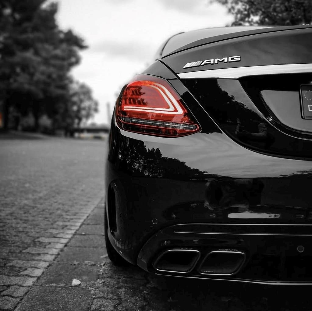 Mercedes-AMG C63 W205 in Schwarz mit V8 Biturbo Motor auf Landstraße bei dramatischem Himmel und Detailaufnahmen von AMG Design und Performance Komponenten