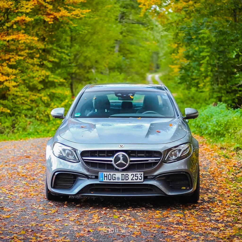 Mercedes-AMG E63 in Frontansicht auf einer mit Herbstlaub bedeckten Waldstraße fotografiert