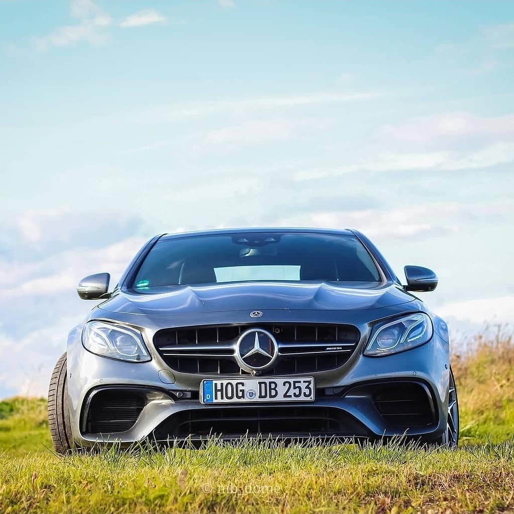 Mercedes-AMG E63 in Frontansicht auf einer Wiese mit blauem Himmel im Hintergrund fotografiert