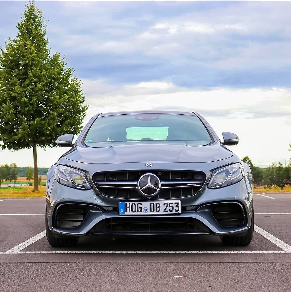 Mercedes-AMG E63 in symmetrischer Frontansicht auf einem Parkplatz unter bewölktem Himmel fotografiert