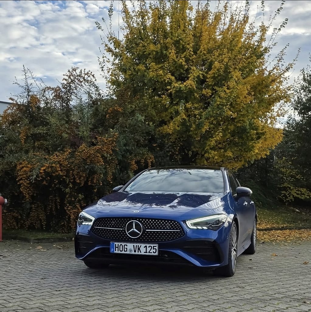Mercedes-Benz CLA Shooting Brake X118 in Blau auf Parkplatz im Herbst mit gelben Blättern und modernem Design