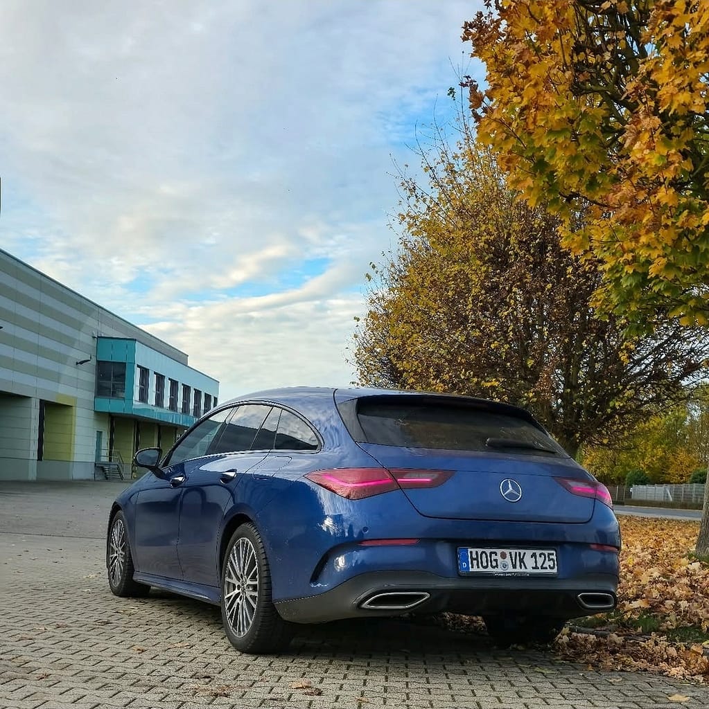 Mercedes-Benz CLA Shooting Brake X118 in Blau auf Parkplatz im Herbst mit gelben Blättern und modernem Design