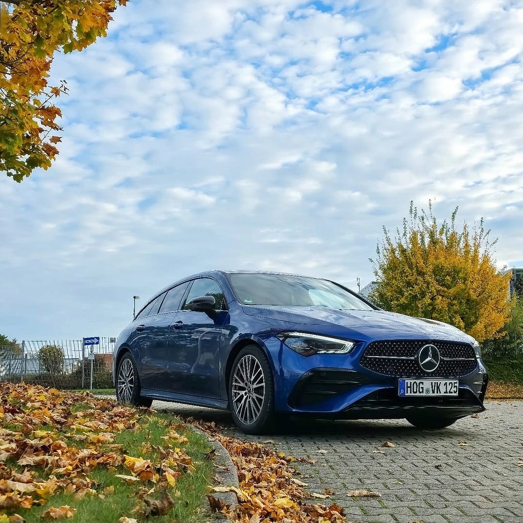 Mercedes-Benz CLA Shooting Brake X118 in Blau auf Parkplatz im Herbst mit gelben Blättern und modernem Design