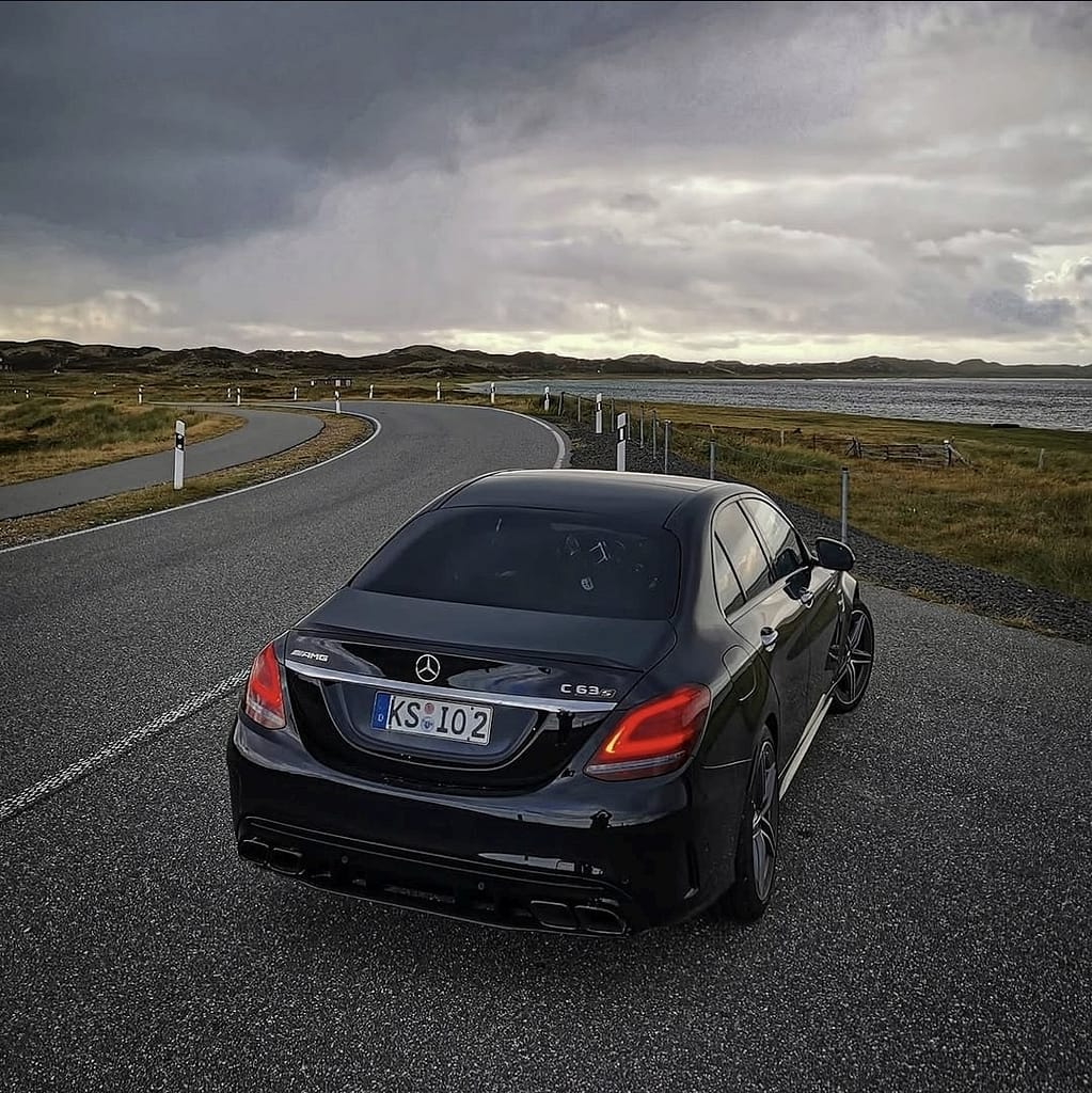 Mercedes-AMG C63 W205 in Schwarz mit V8 Biturbo Motor auf Landstraße bei dramatischem Himmel und Detailaufnahmen von AMG Design und Performance Komponenten