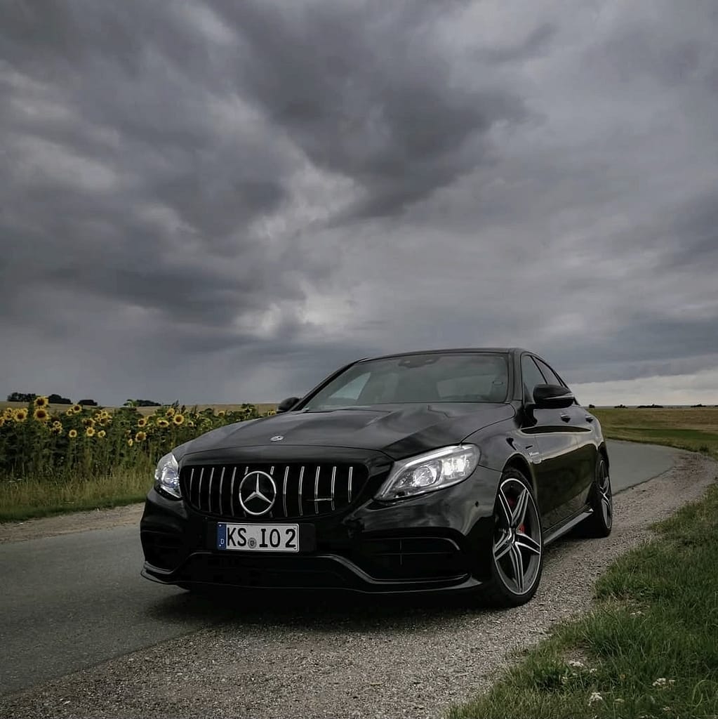 Mercedes-AMG C63 W205 in Schwarz mit V8 Biturbo Motor auf Landstraße bei dramatischem Himmel und Detailaufnahmen von AMG Design und Performance Komponenten