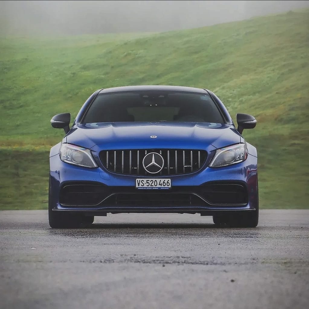 Frontansicht eines blauen Mercedes-AMG C63 S Coupé vor Berglandschaft