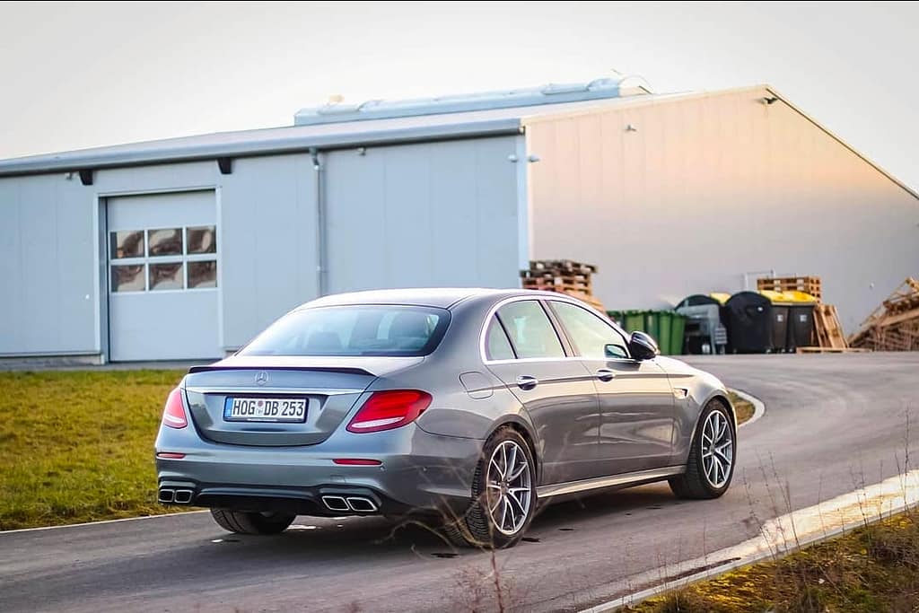 Mercedes-AMG E63 in Heck-Seitenansicht auf einer Straße neben einem Industriegebäude im warmen Abendlicht fotografiert