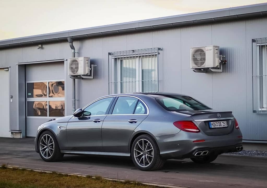 Mercedes-AMG E63 in Heck-Seitenansicht vor einem modernen Industriegebäude fotografiert