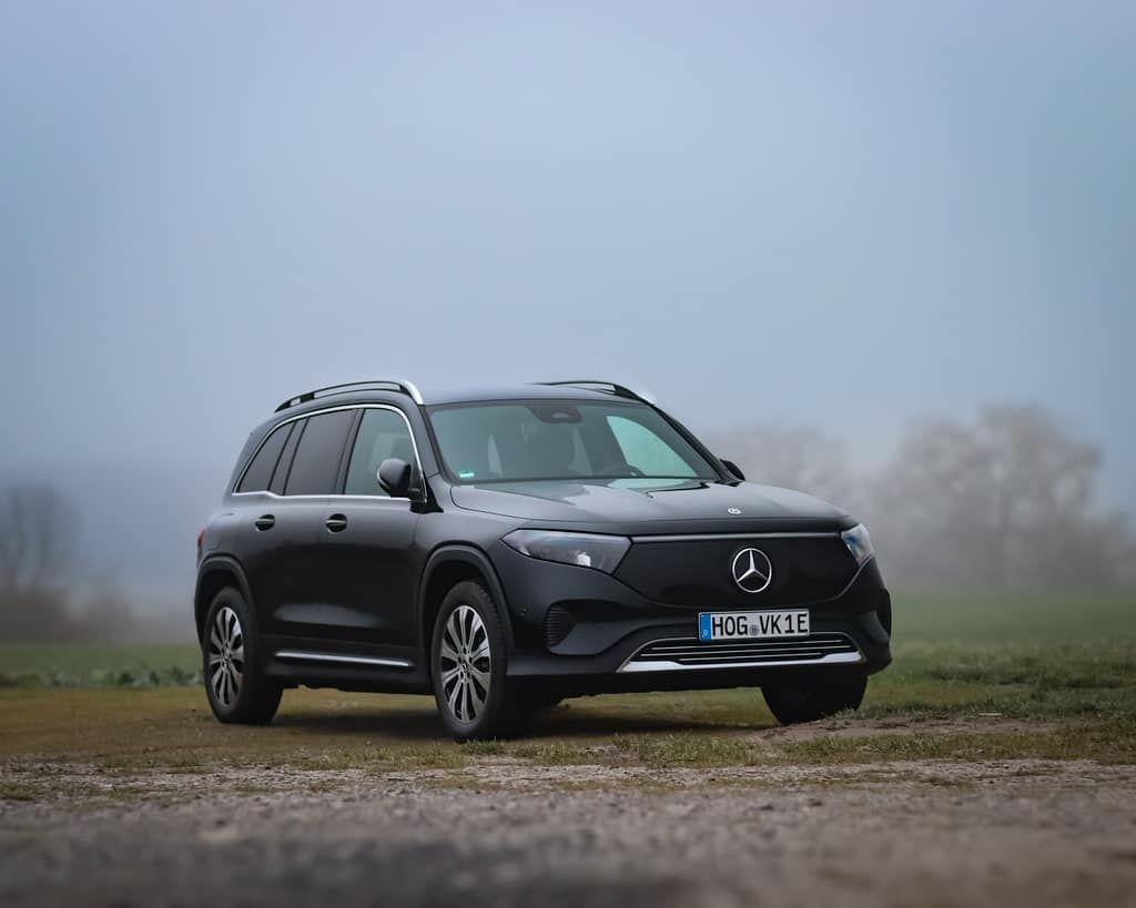 Mercedes-Benz EQB Elektro SUV in schwarzer Lackierung auf unbefestigtem Weg in nebliger Landschaft mit Front-, Seiten- und Heckansicht