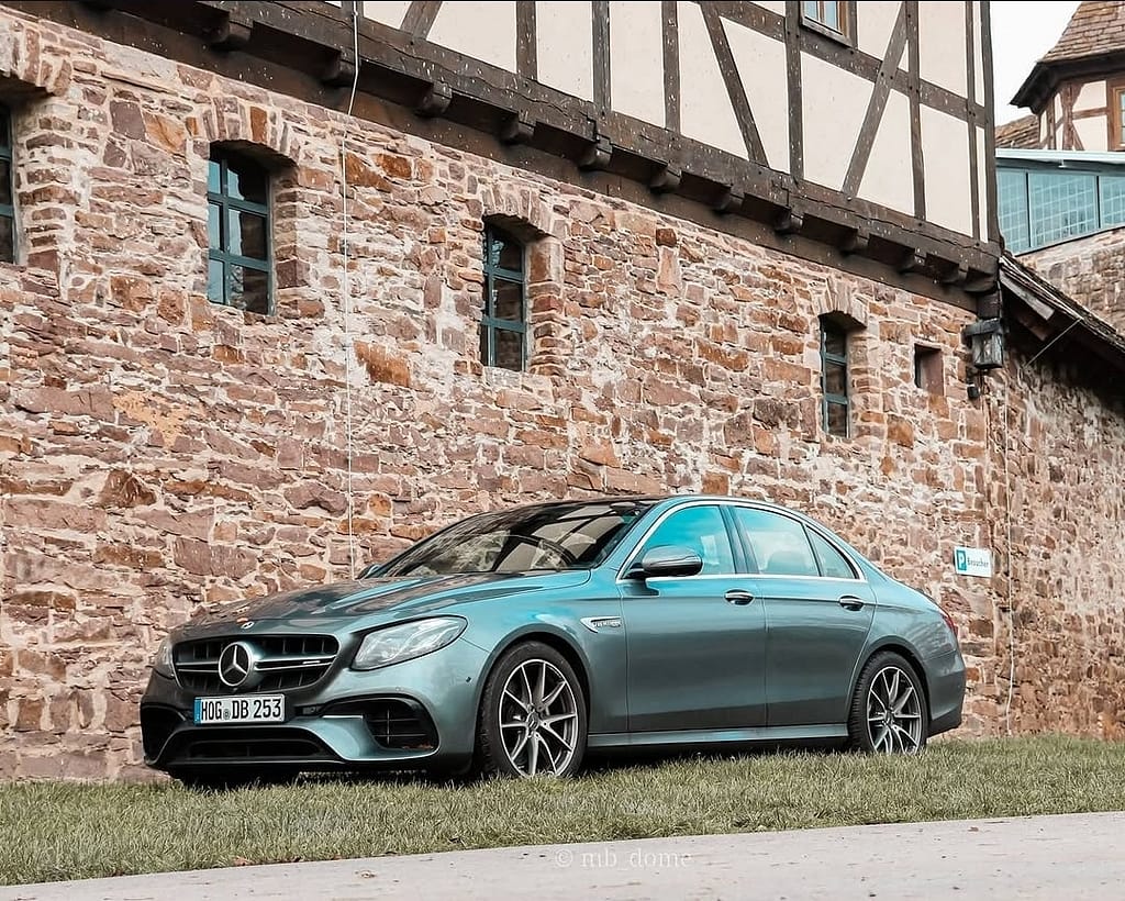 Mercedes-AMG E63 in Seitenansicht vor einer historischen Fachwerk- und Natursteinwand fotografiert