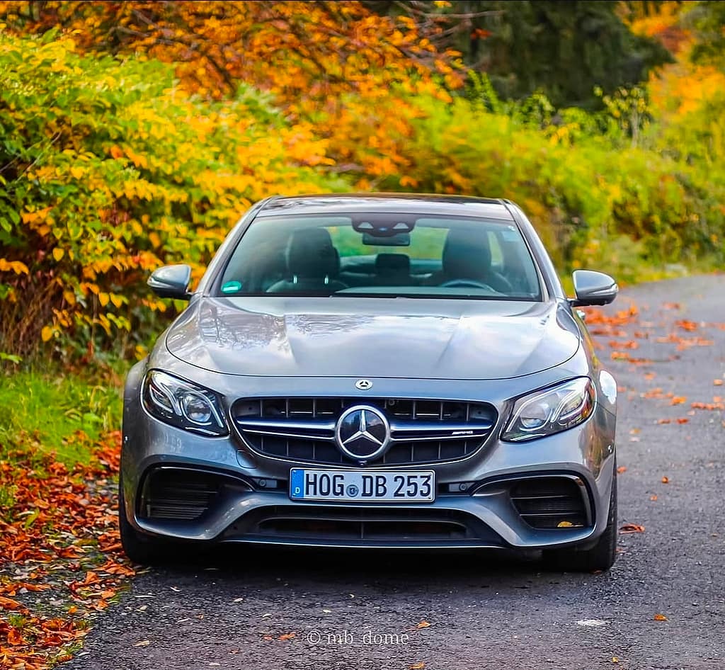 Mercedes-AMG E63 in Frontansicht auf einer Straße mit herbstlichen Bäumen und buntem Laub im Hintergrund fotografiert