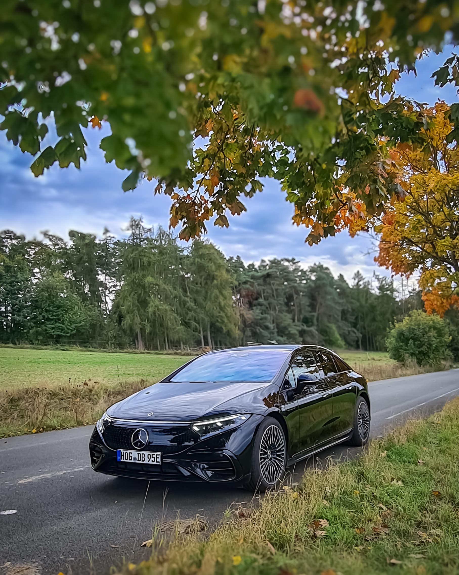 Mercedes-Benz EQS 450+ Frontansicht auf Landstraße unter Herbstbaum