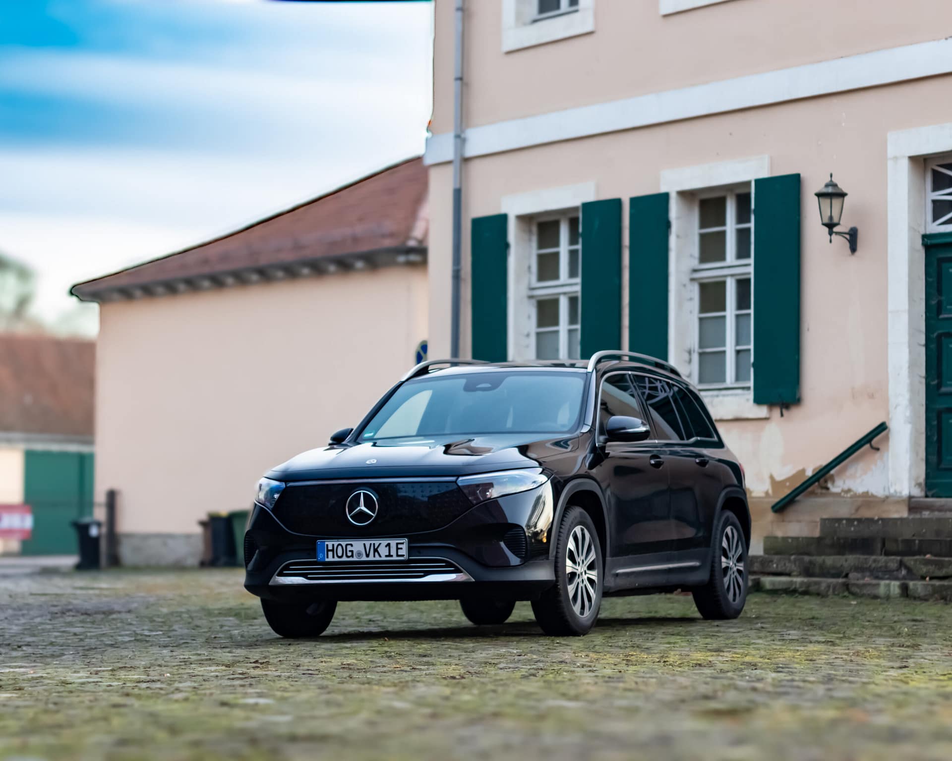 Mercedes-Benz EQB Elektro SUV Frontansicht vor historischem Gebäude mit grünen Fensterläden