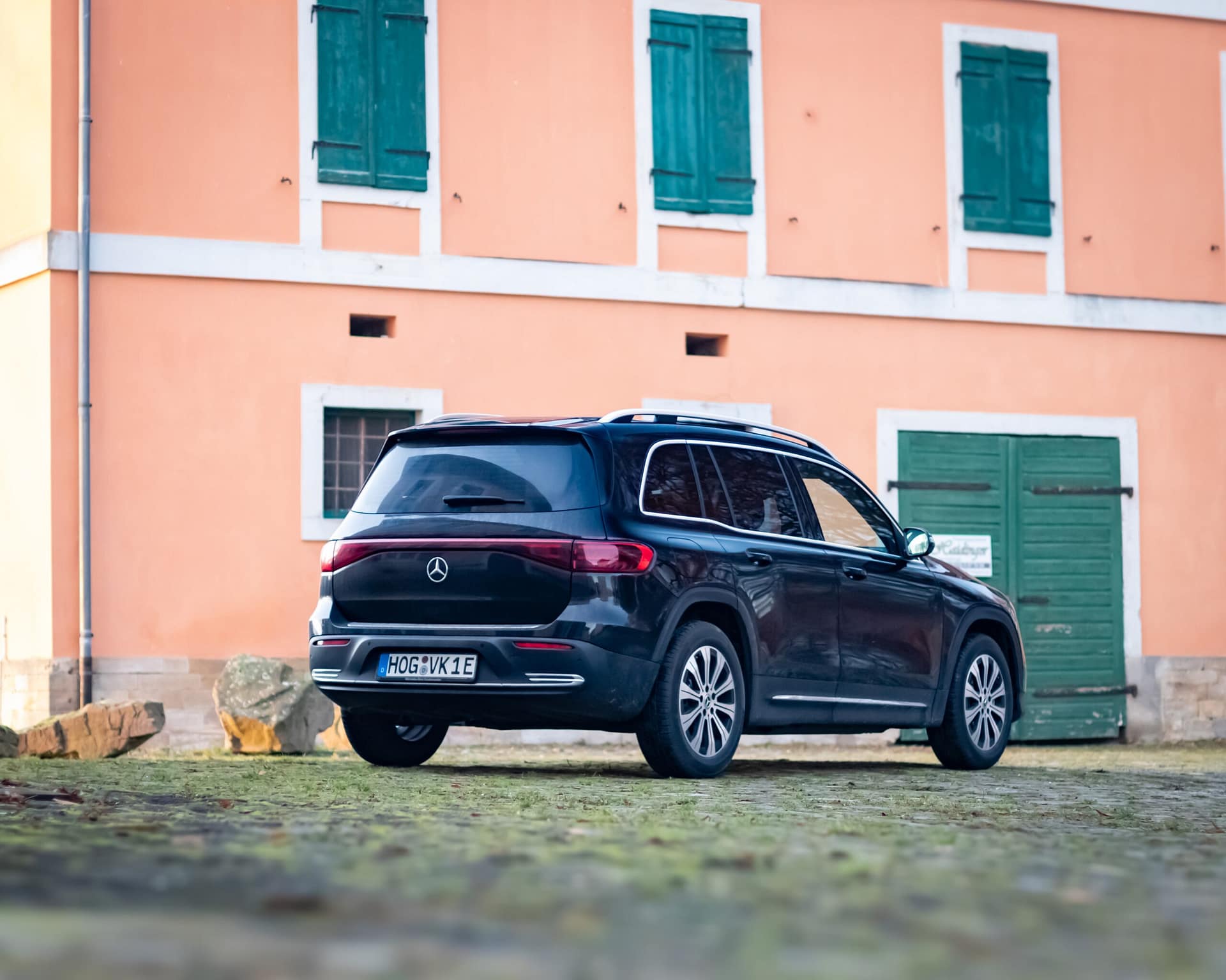 Mercedes-Benz EQB Elektro SUV Heckansicht vor historischem Gebäude mit orangefarbener Fassade