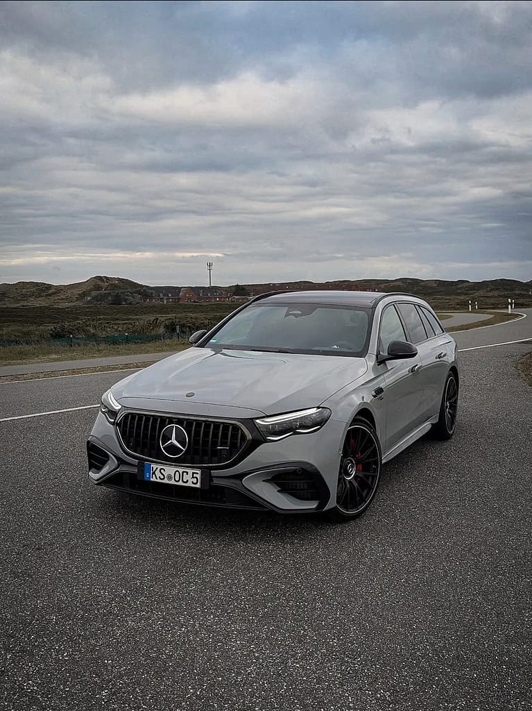 Mercedes-AMG E53 T-Modell Frontansicht auf Küstenstraße unter bewölktem Himmel