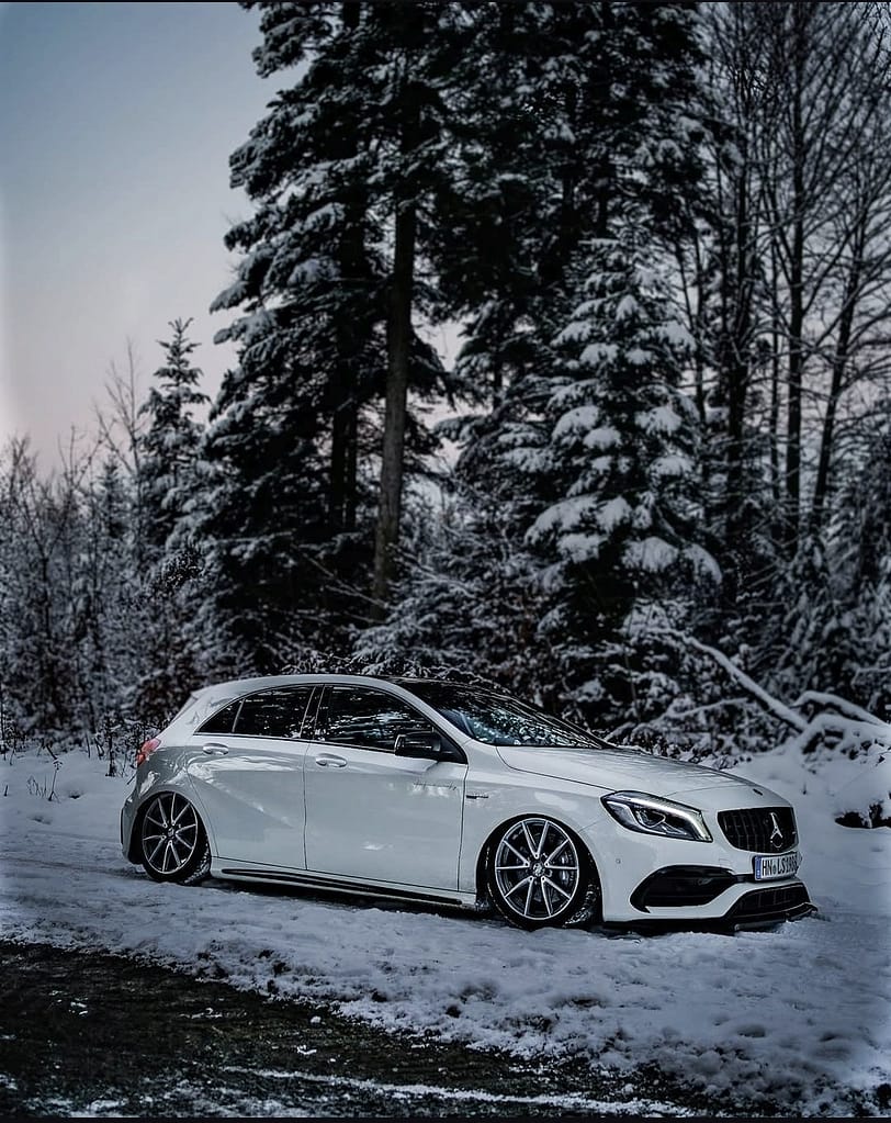 Weißer Mercedes-AMG A45 W176 als Seitenansicht im Schnee mit sportlichen AMG Felgen und Winterkulisse