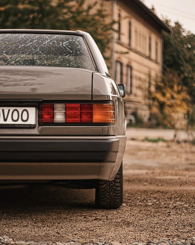 Mercedes-Benz 190E W201 Klassiker in warmer Lichtstimmung fotografiert auf urbanem Gelände – Automotive Fotografie Detailaufnahme Front und Seitenansicht
