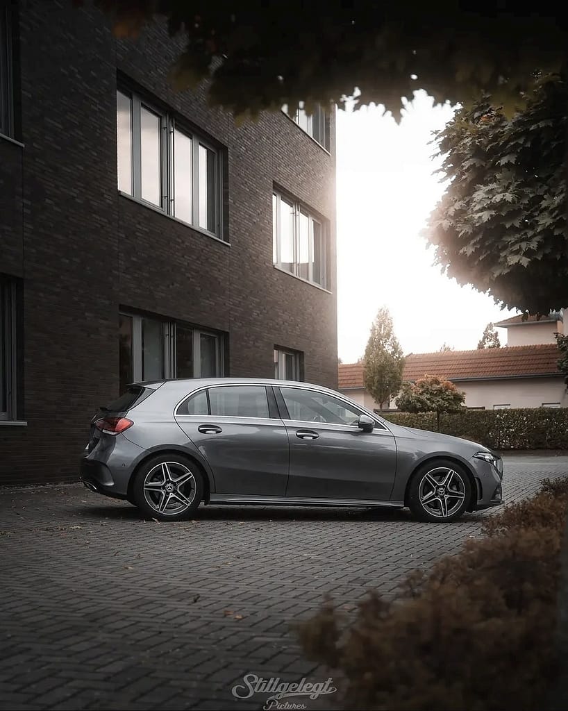 Mercedes-Benz A-Klasse W177 in grauer Lackierung in Seitenansicht vor moderner Architektur bei Sonnenuntergang