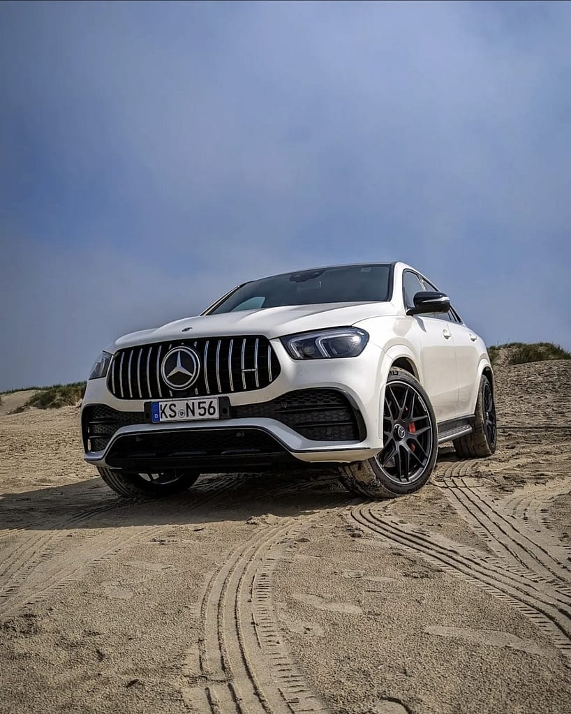 Mercedes-AMG GLE 53 Coupé C167 in weiß auf Sanddünen mit sportlicher Front und AMG Felgen.