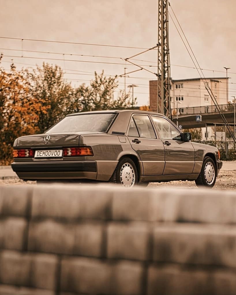 Mercedes-Benz 190E W201 Klassiker in warmer Lichtstimmung fotografiert auf urbanem Gelände – Automotive Fotografie Detailaufnahme Front und Seitenansicht