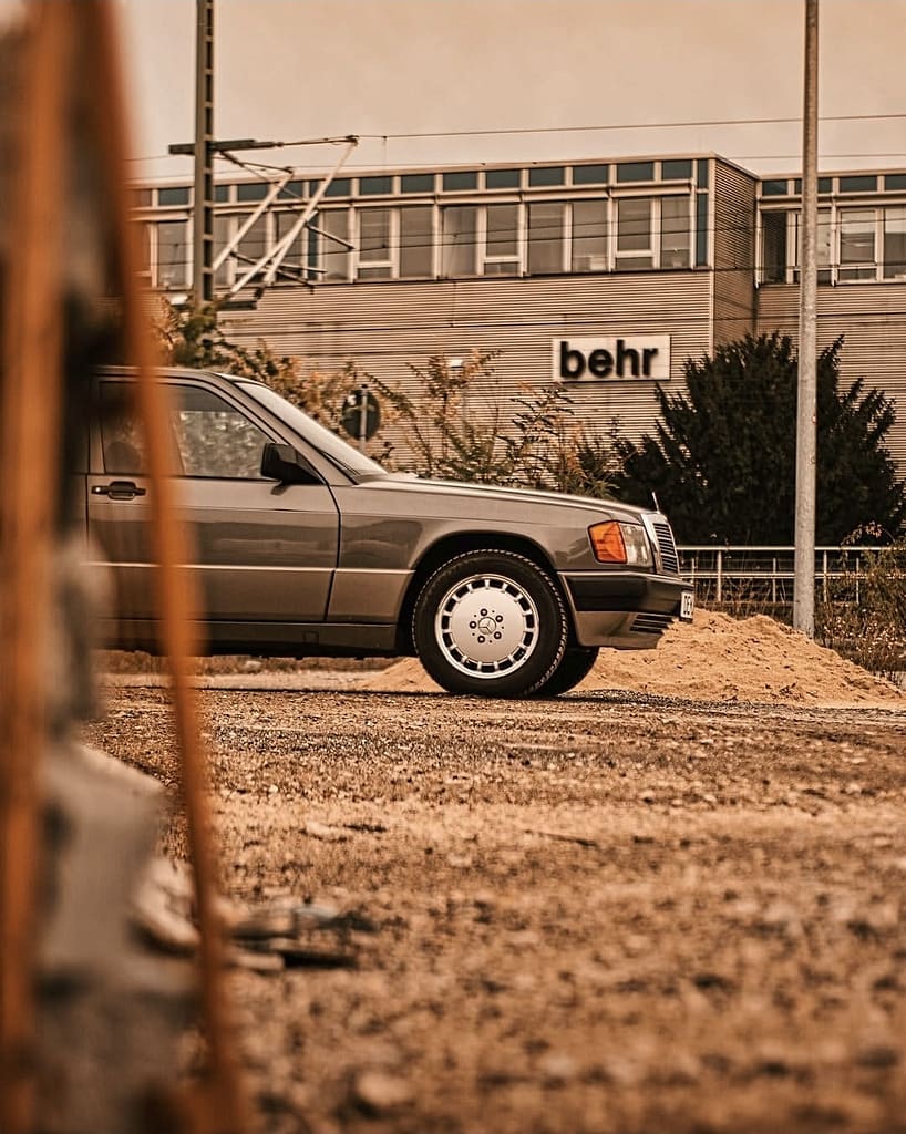 Mercedes-Benz 190E W201 Klassiker in warmer Lichtstimmung fotografiert auf urbanem Gelände – Automotive Fotografie Detailaufnahme Front und Seitenansicht